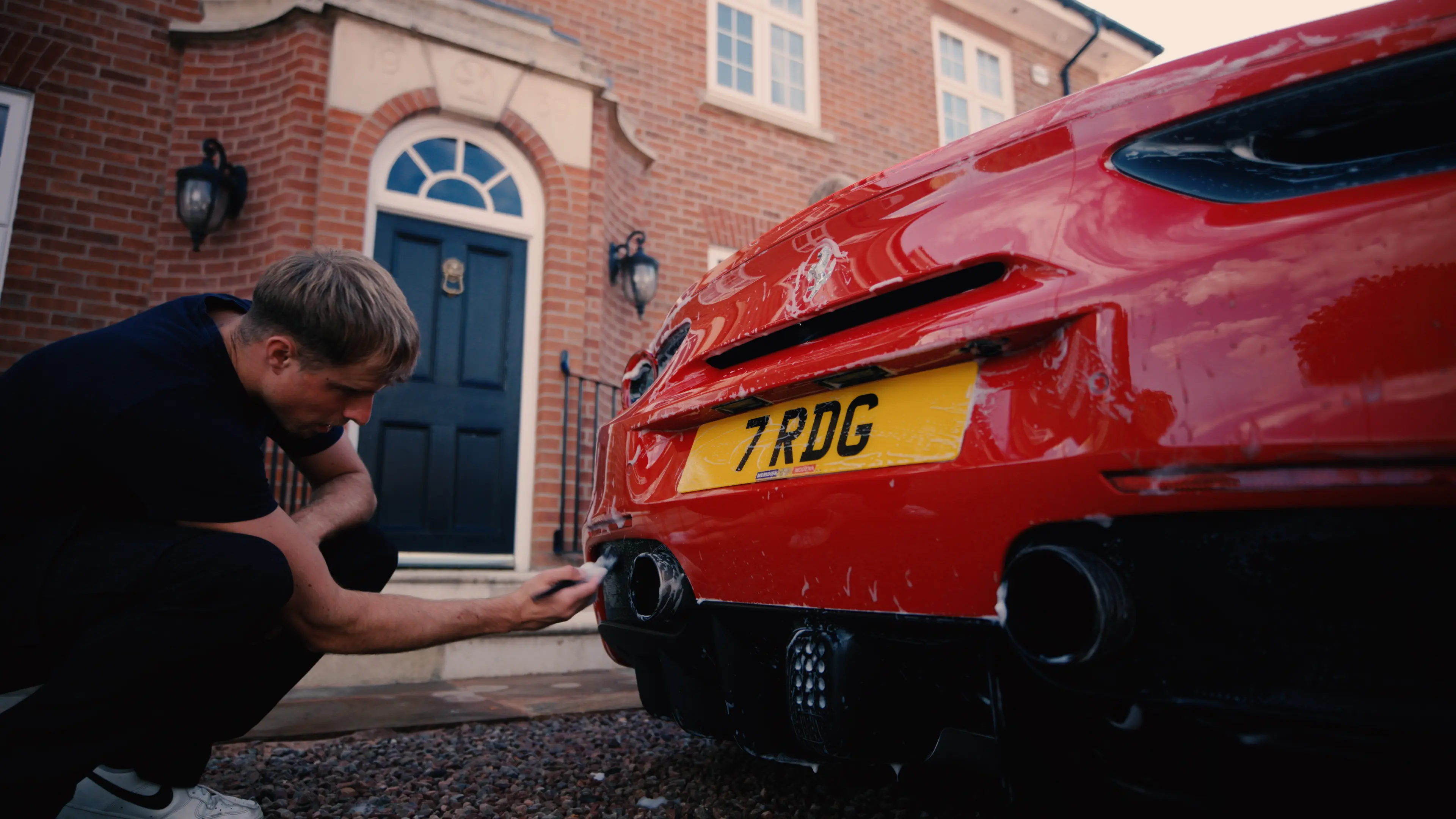 M&L Detailing team member cleaning the rear of a red Ferrari