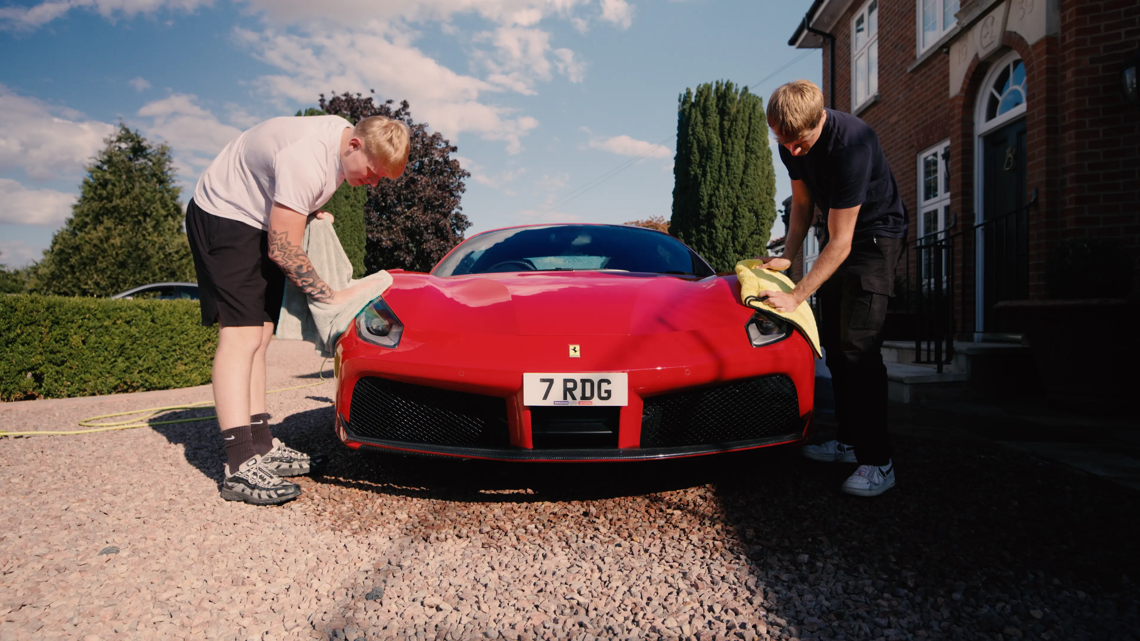 Two M&L Detailing team members hand-finishing a red Ferrari